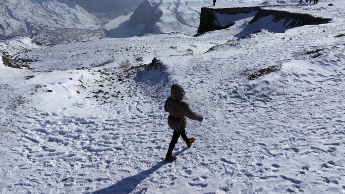 航拍女孩在冬季新疆安集海大峡谷悬崖边玩耍
