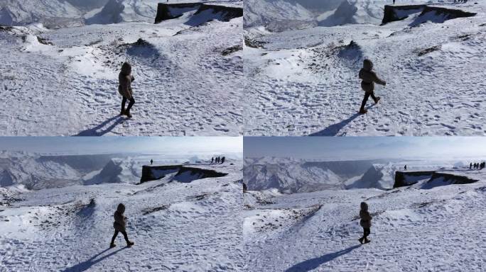 航拍女孩在冬季新疆安集海大峡谷悬崖边玩耍