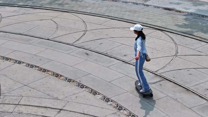 一名年轻美少女在公园广场独自一人练习滑板