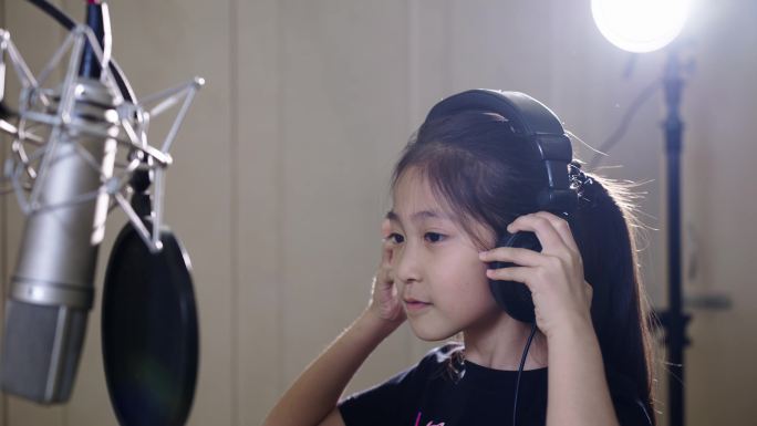 录音棚小歌手小女孩戴上耳机录制童声歌曲