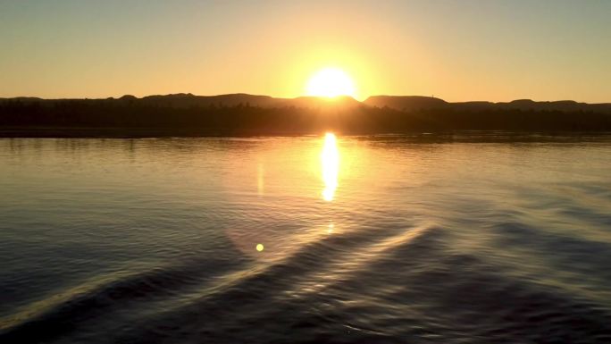 河轮行驶在清晨黄昏洒满阳光的河面之上