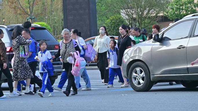 放学高峰期堵车，小学生穿梭在车辆中过马路