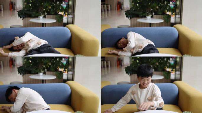 可爱的中国小男孩大笑着躺倒在沙发上