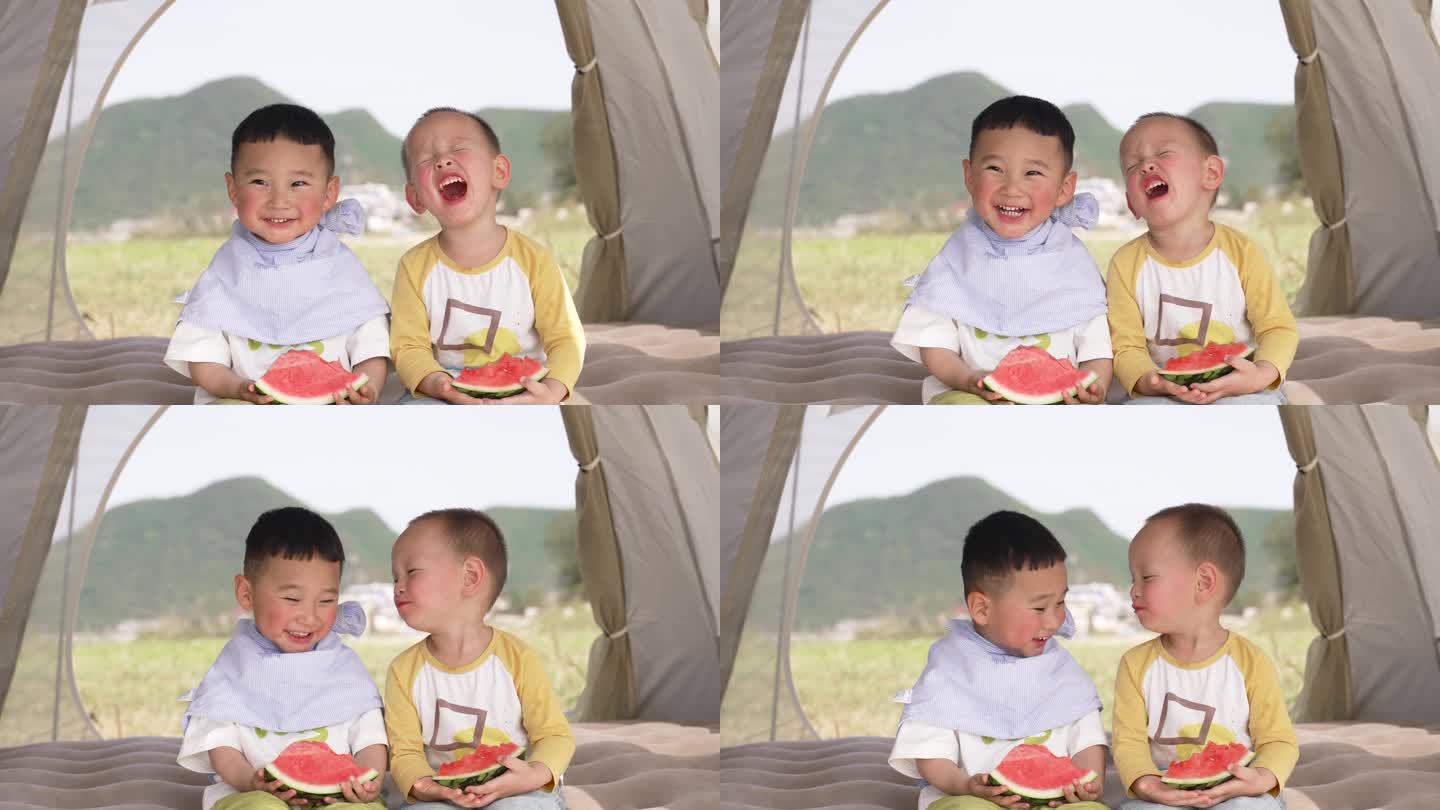 小孩吃西瓜-两个小孩坐在帐篷里吃西瓜嬉笑