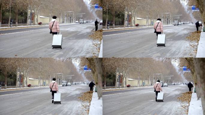 下雪雪地道路泥泞年轻人拉着行李箱赶路背影