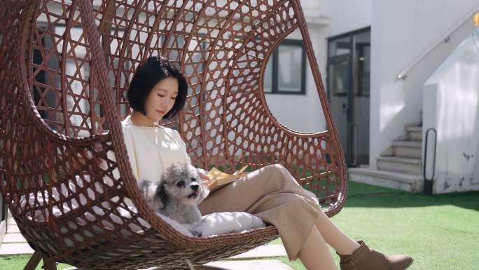 快乐的年轻女子和宠物狗坐在吊椅上