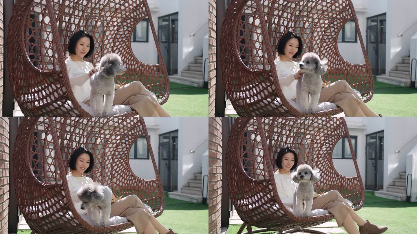 快乐的年轻女子和宠物狗坐在吊椅上