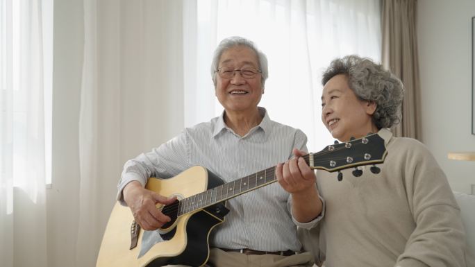 快乐的老年夫妇在家弹吉他唱歌