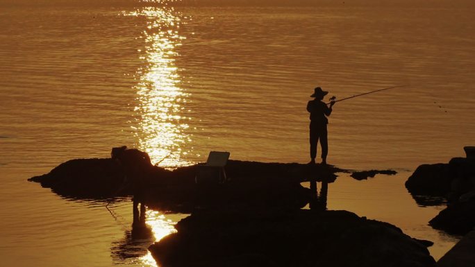日落时在岩石上钓鱼的人们