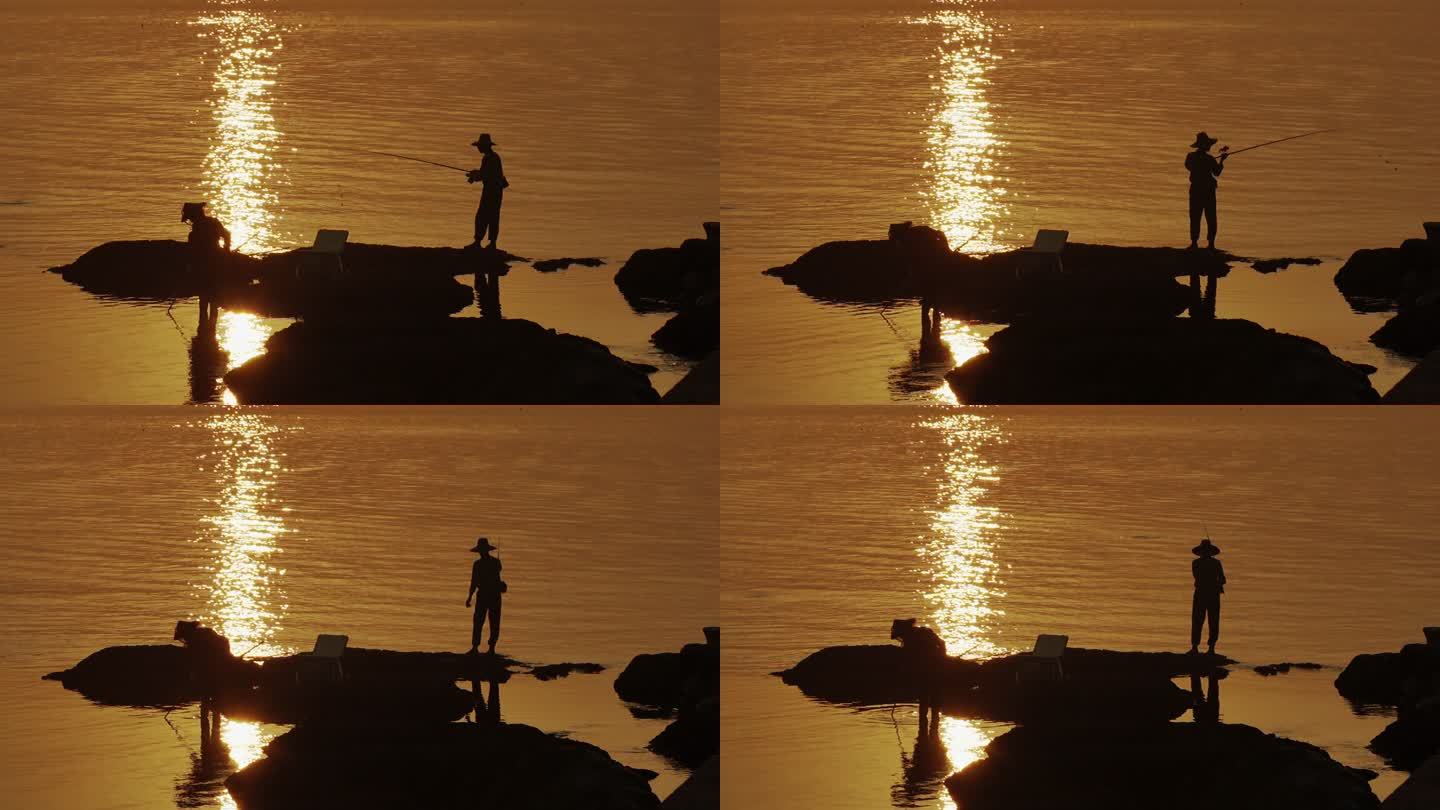 日落时在岩石上钓鱼的人们