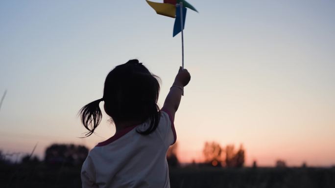 夕阳下小孩在田野玩耍玩风车