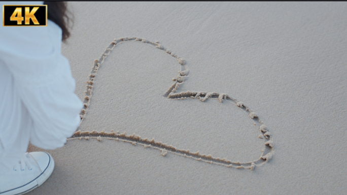 在沙子上画心形的女人 沙滩上的心被冲走