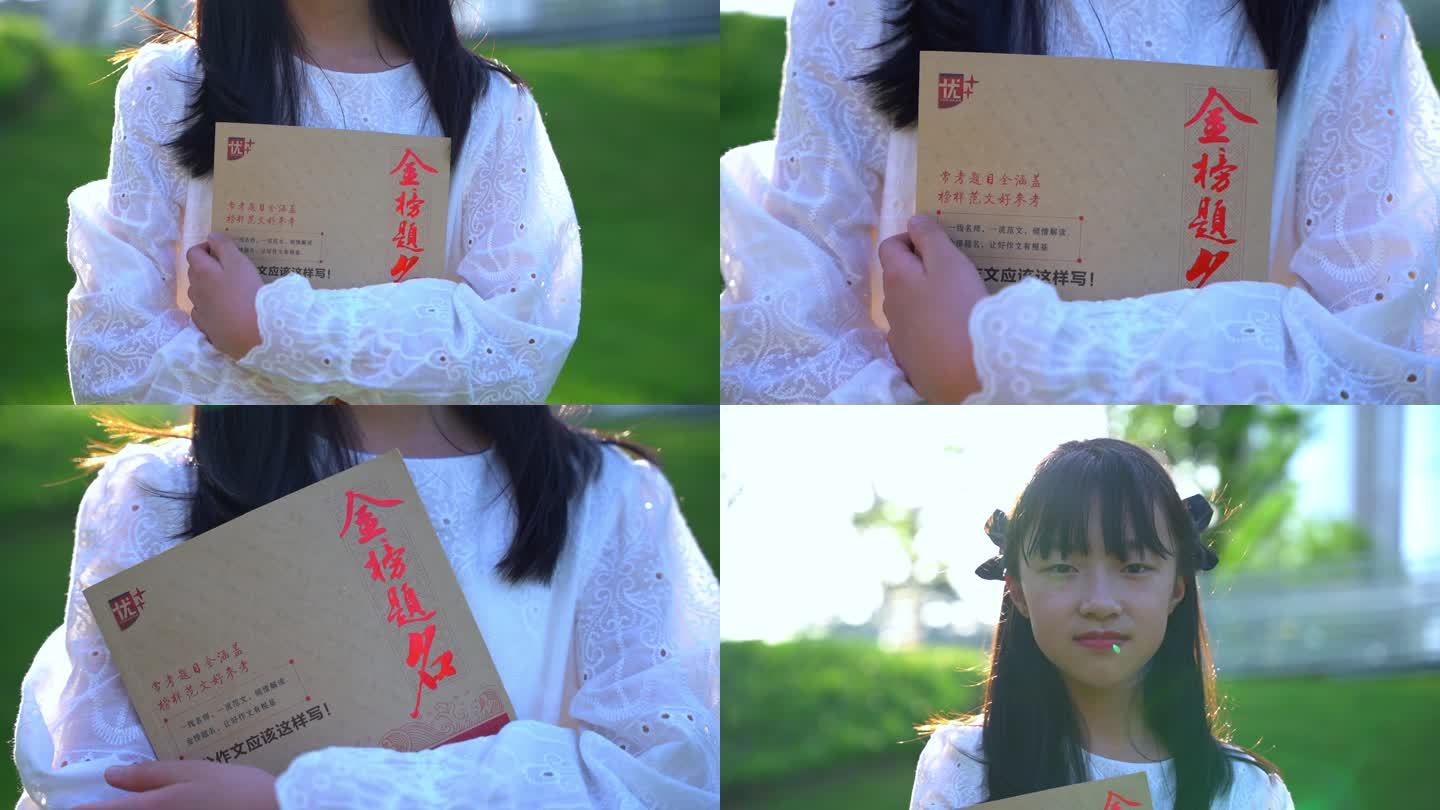 阳光草坪抱着一本金榜题名书籍的女孩