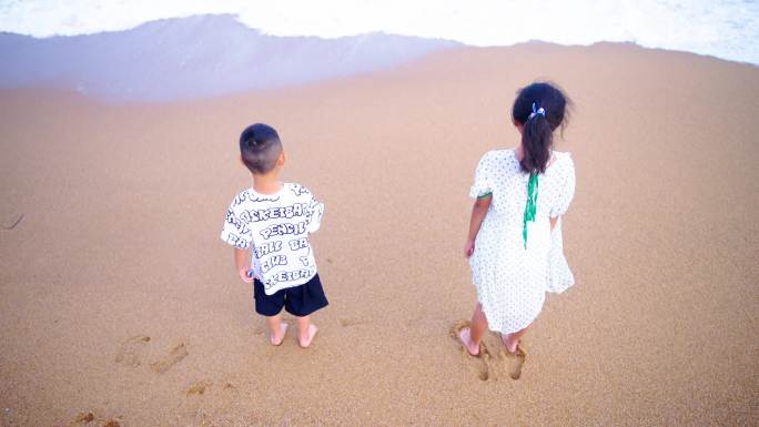 小孩站在海边沙滩上