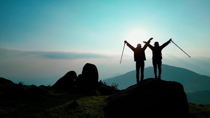 登山的人拥抱天空拥抱阳光胜利登顶欢呼庆祝