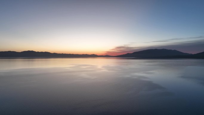 清晨朝霞倒映在赛里木湖平静的湖面航拍