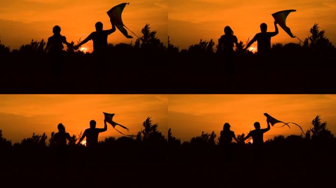 夕阳下情侣拿着风筝奔跑
