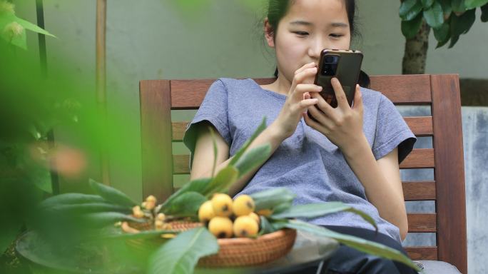 在别墅院子里刷手机的开心漂亮女孩