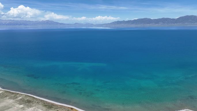 航拍晴天新疆赛里木湖清澈的蓝绿色渐变湖水