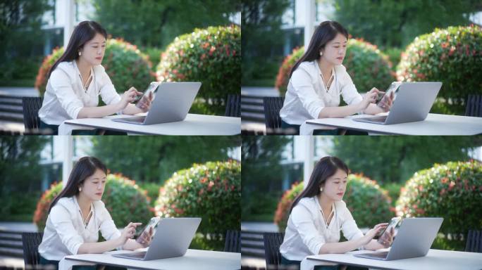 职业女性户外使用笔记本电脑和手机办公