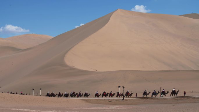 青海甘肃敦煌名沙丘旅客骑着骆驼行走在沙漠