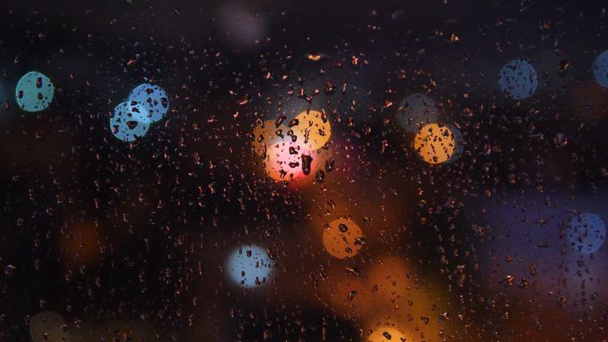 下雨天窗户玻璃上的雨点落下虚化光斑