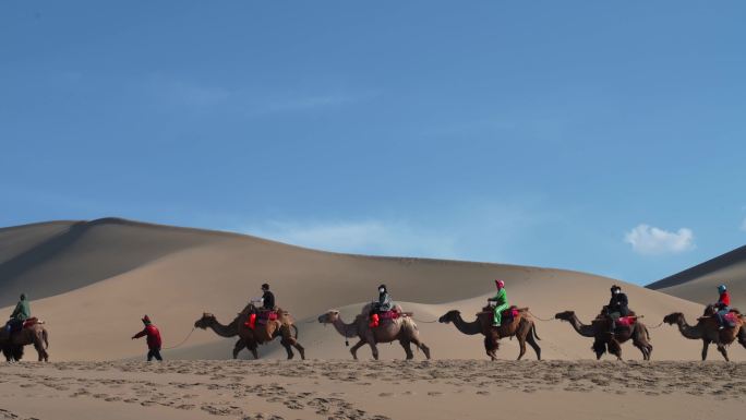 青海甘肃敦煌名沙丘旅客骑着骆驼行走在沙漠