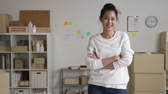 自信的年轻亚洲女性零售商，企业家，在线商店dropshipping小企业主站在配送仓库里拿着包裹箱看