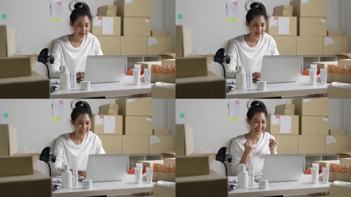 亚洲女网上卖家在笔记本电脑上确认顾客的订单。在仓库工作的电子商务企业主。