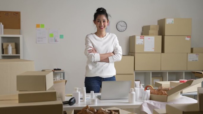 自信的年轻亚洲女性零售商，企业家，在线商店dropshipping小企业主站在配送仓库里拿着包裹箱看