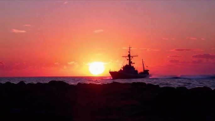 夕阳下太阳剪影海面上的一艘军舰