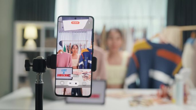 特写手机屏幕记录亚洲女士视频博主看手机相机评论毛衣新系列直播在IG网上销售故事卷抖音在家工作室工作。