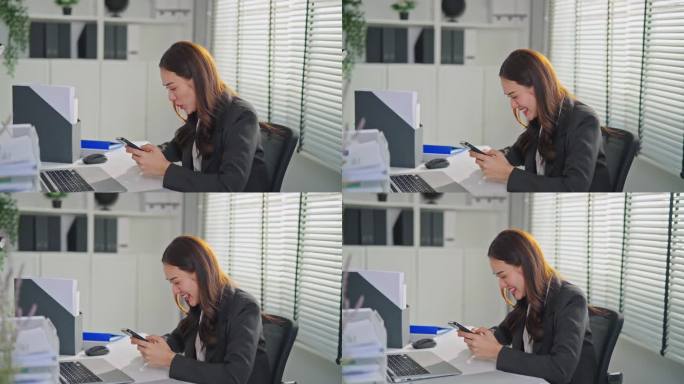 亚洲快乐女商人在办公室工作时刷智能手机。在公司工作场所，穿着正装坐在办公桌上用手机搜索社交媒体的漂亮