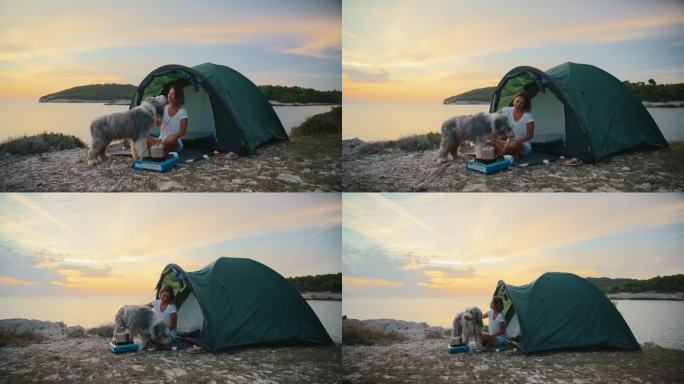 快乐的女人和忠诚的狗享受黄昏的海边露营