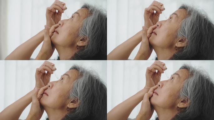 上了年纪的亚洲妇女正在往眼睛里滴眼药水