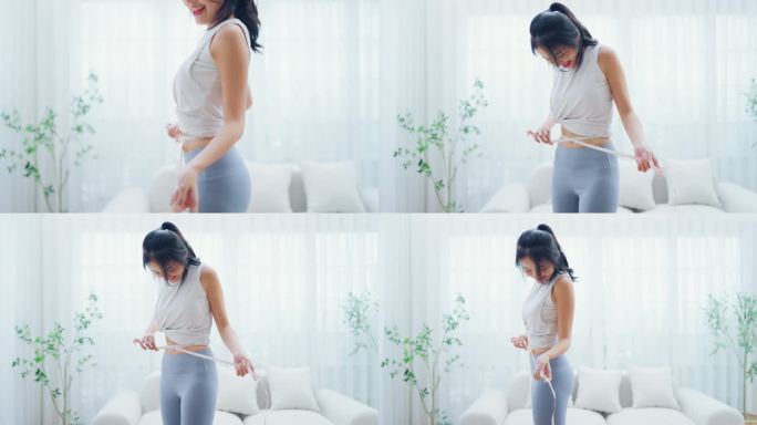 穿着运动服的年轻亚洲女子用卷尺量腰围。饮食健康理念。身材苗条