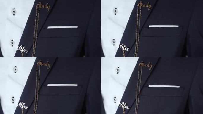 新郎深蓝色西装的特写，上面有个性化的金色名牌