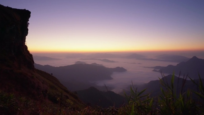 日出时在山上欣赏大自然美景的田园风光。高山和山脊被云雾包围着进入清晨。