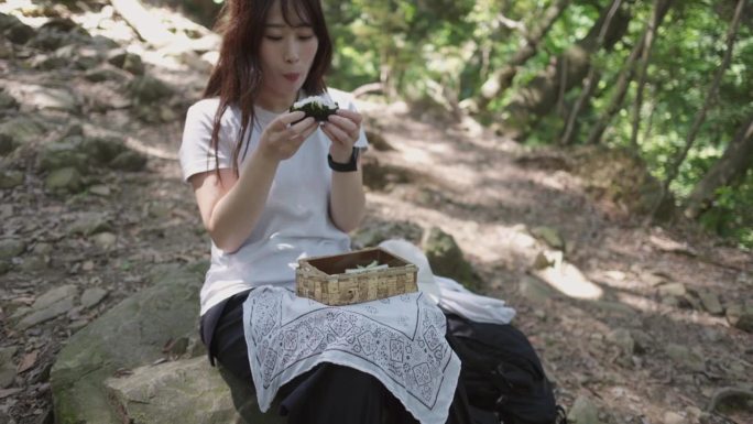 女徒步者坐在山间小道上吃午饭——仰头