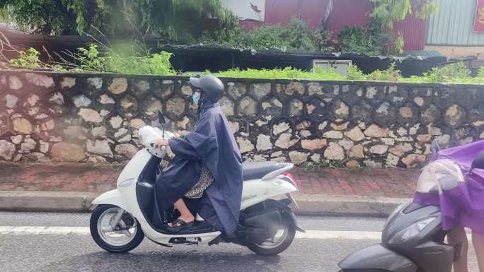 摩托车头盔雨衣雨天骑车人群冒雨开摩托行驶