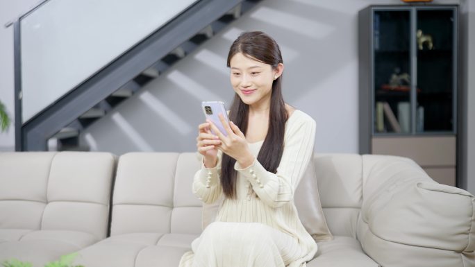 女子坐在沙发上玩手机视频通话