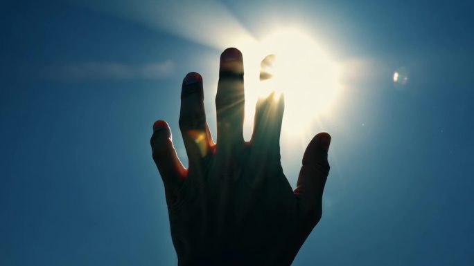 人类之手剪影和深蓝的天空阳光。