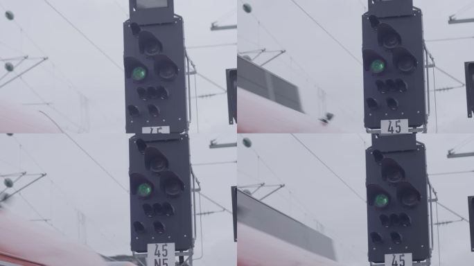 铁路信号灯上的绿灯，近景，背景中行驶的火车模糊