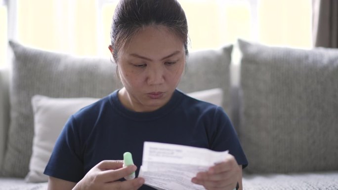 一名妇女一边服药一边阅读药物手册