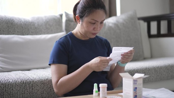 一名妇女一边服药一边阅读药物手册