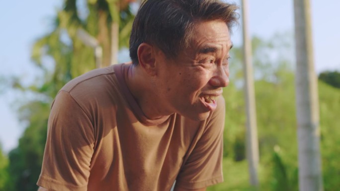 亚洲老人在花园里运动时感到疲惫不堪。迷人的成熟老年运动员在公园里练习健身时深呼吸休息。