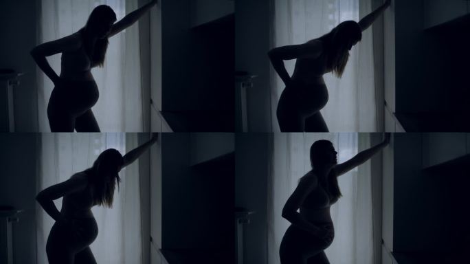 孕妇临产的剪影。她疼了，摸了摸肚子。