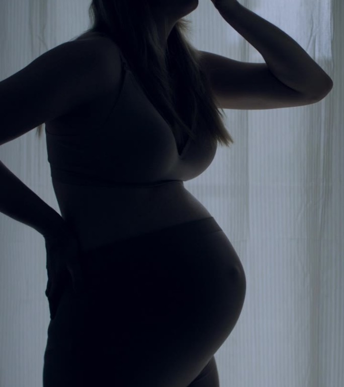 孕妇临产的剪影。她疼了，摸了摸肚子。