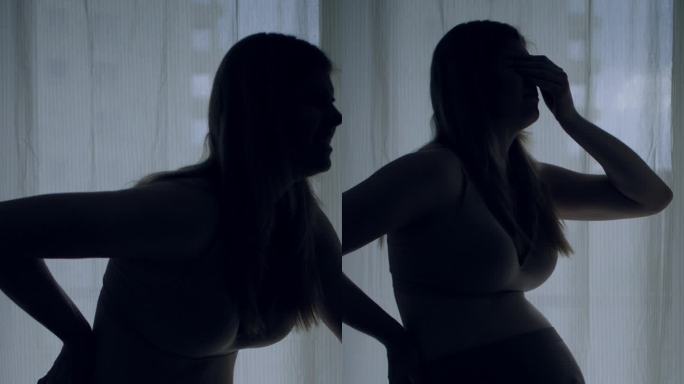 孕妇临产的剪影。她疼了，摸了摸肚子。