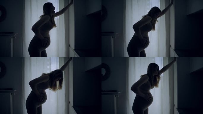 孕妇临产的剪影。她疼了，摸了摸肚子。